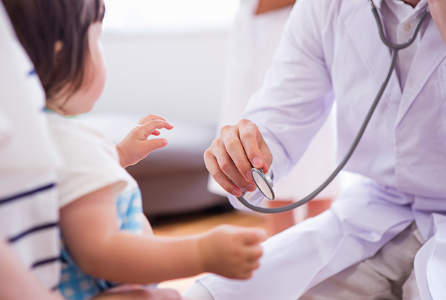 保護者の膝の上で診察を受けいている子ども